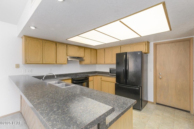 kitchen featuring dark countertops, a sink, black appliances, a peninsula, and under cabinet range hood