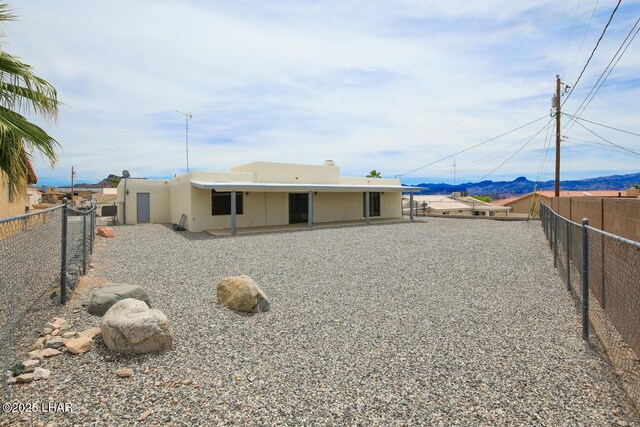 rear view of house with a mountain view, a fenced backyard, and stucco siding