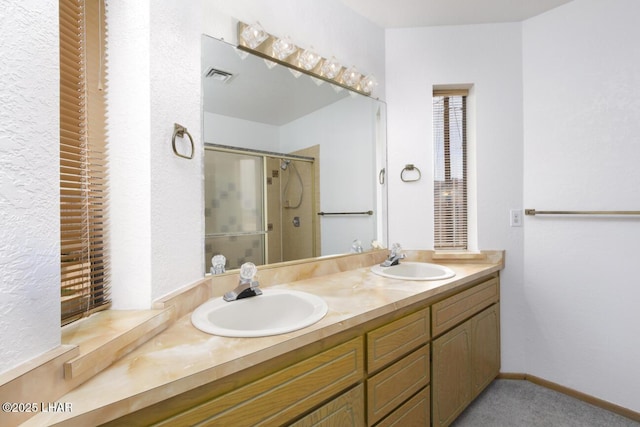full bath with visible vents, a sink, double vanity, and a shower stall