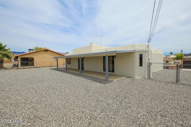 rear view of house featuring fence, a gate, stucco siding, and a patio area