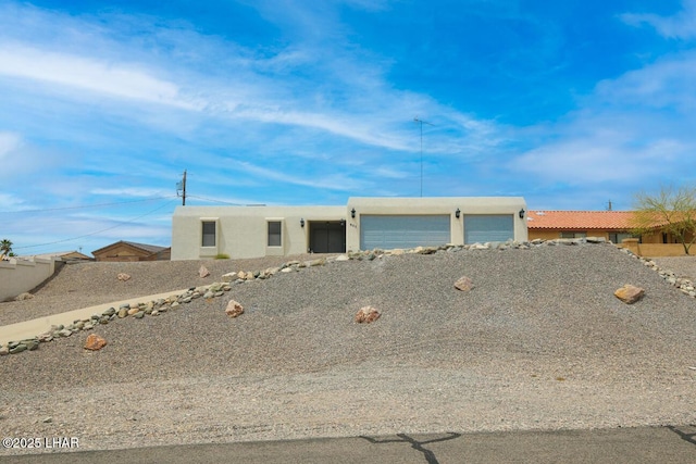 view of front of house with stucco siding, fence, and a garage