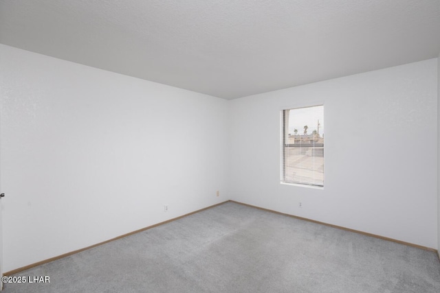empty room featuring light colored carpet and baseboards