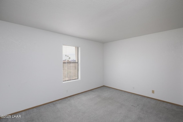 unfurnished room with baseboards and light colored carpet