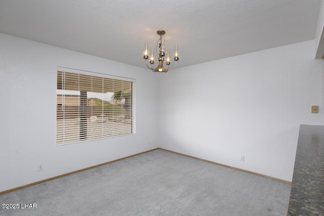 carpeted spare room with baseboards and a notable chandelier