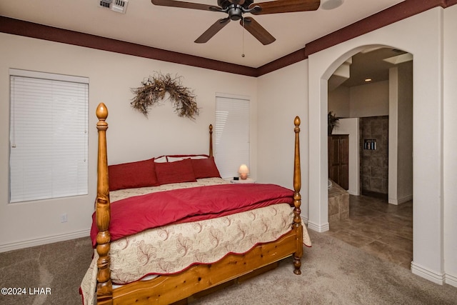 carpeted bedroom featuring visible vents, arched walkways, and a ceiling fan