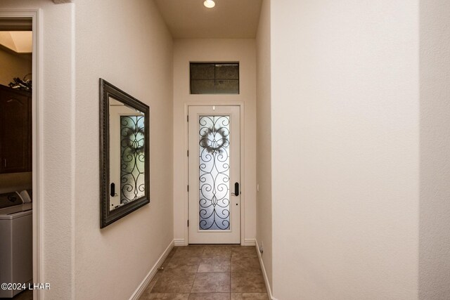 doorway with light tile patterned floors, washer / dryer, and baseboards