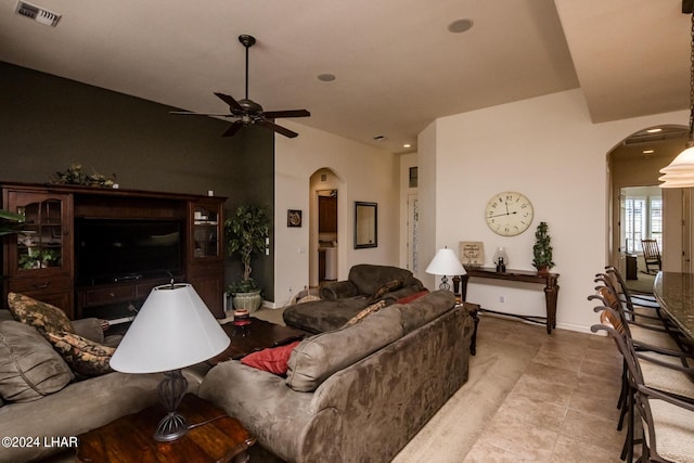 tiled living area with baseboards, visible vents, arched walkways, and ceiling fan