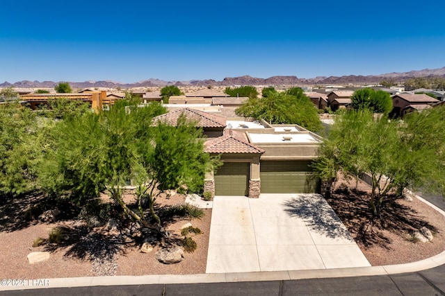 view of front of house featuring stucco siding, driveway, a tile roof, stone siding, and a mountain view