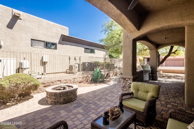 view of patio / terrace featuring grilling area, ceiling fan, fence, an outdoor fire pit, and an outdoor kitchen