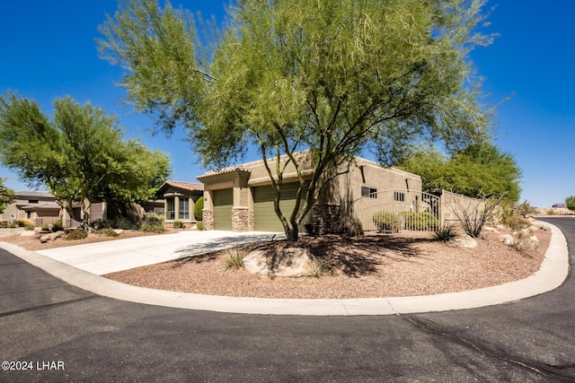 view of front of property with stucco siding, driveway, a fenced front yard, an attached garage, and a tiled roof