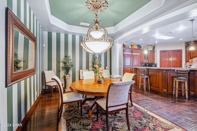 dining room featuring dark wood-type flooring and a raised ceiling