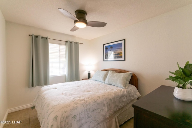 bedroom featuring a ceiling fan, baseboards, and light tile patterned flooring