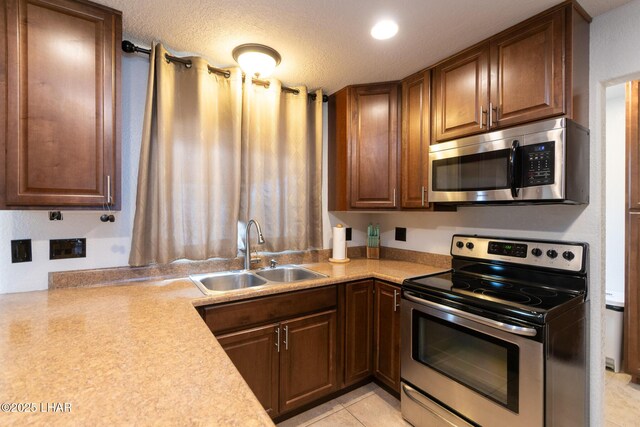 kitchen featuring light countertops, a textured ceiling, appliances with stainless steel finishes, and a sink