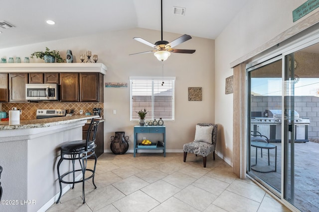 kitchen with visible vents, backsplash, dark brown cabinetry, lofted ceiling, and appliances with stainless steel finishes