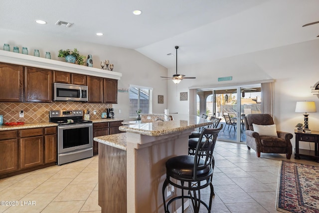 kitchen featuring visible vents, backsplash, a kitchen breakfast bar, stainless steel appliances, and a ceiling fan