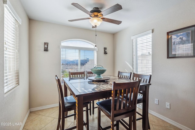 dining area featuring a ceiling fan, light tile patterned floors, a healthy amount of sunlight, and baseboards