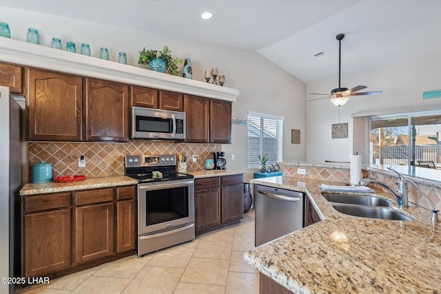 kitchen with plenty of natural light, a sink, decorative backsplash, vaulted ceiling, and appliances with stainless steel finishes