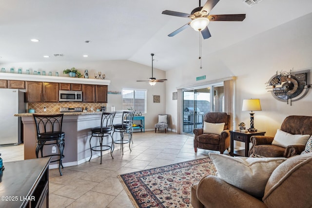 living area featuring visible vents, baseboards, lofted ceiling, light tile patterned floors, and a ceiling fan