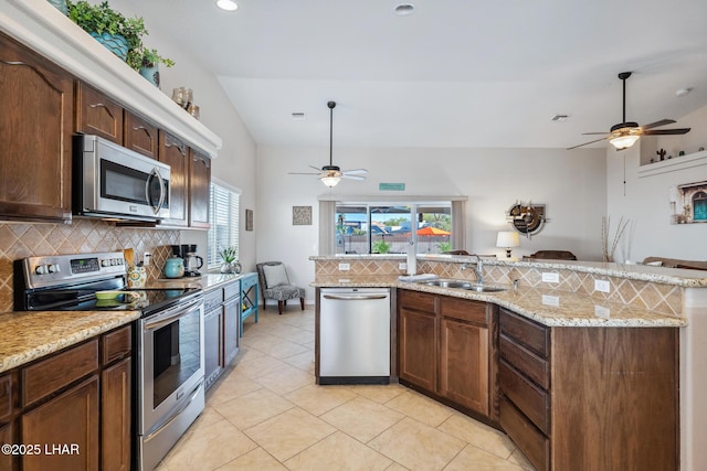 kitchen with decorative backsplash, appliances with stainless steel finishes, open floor plan, and a sink