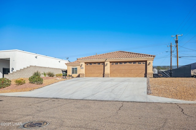 view of front facade with stucco siding, stone siding, concrete driveway, and a tile roof