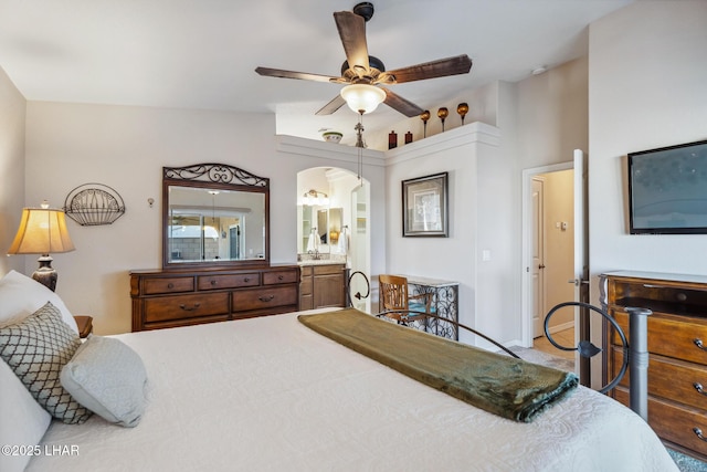 bedroom featuring a ceiling fan, arched walkways, and connected bathroom