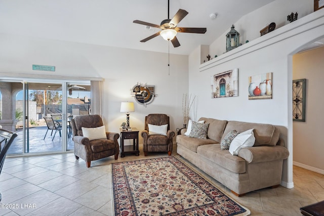 living room with a towering ceiling, baseboards, ceiling fan, and light tile patterned flooring