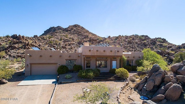 pueblo revival-style home with a garage and a mountain view