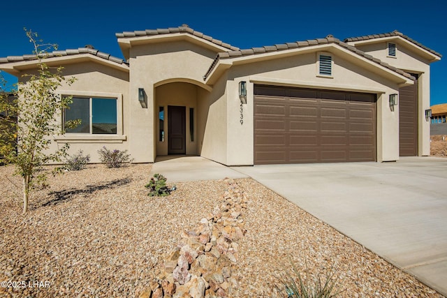 mediterranean / spanish home with a garage, a tile roof, concrete driveway, and stucco siding