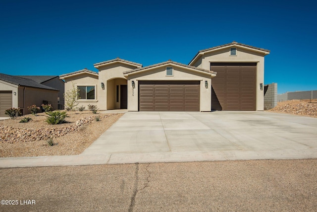 mediterranean / spanish home with a tile roof, driveway, an attached garage, and stucco siding