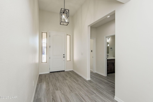 entryway with light wood-style flooring, a high ceiling, and baseboards