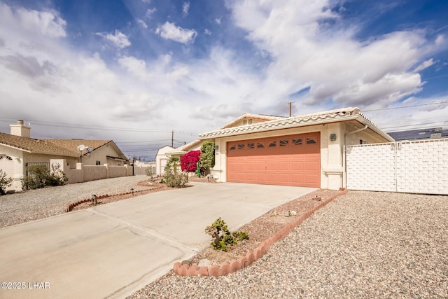 ranch-style home featuring an attached garage, a tile roof, fence, concrete driveway, and stucco siding