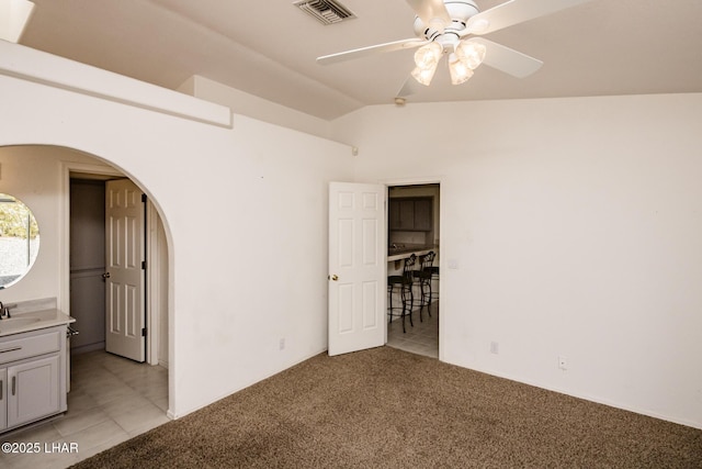 unfurnished bedroom featuring arched walkways, a sink, visible vents, and light colored carpet