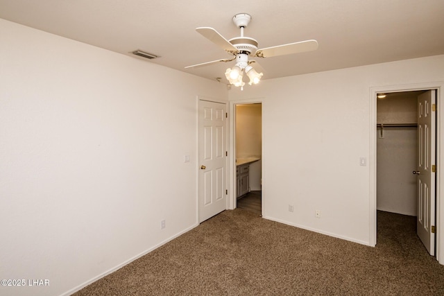 unfurnished bedroom featuring carpet floors, visible vents, baseboards, a closet, and a walk in closet