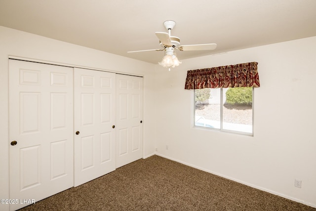 unfurnished bedroom with dark colored carpet, a closet, ceiling fan, and baseboards