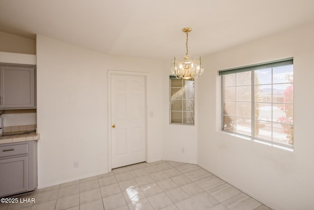 unfurnished dining area featuring a chandelier and baseboards