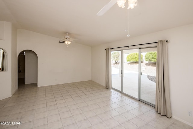 spare room featuring light tile patterned floors, arched walkways, vaulted ceiling, and a ceiling fan