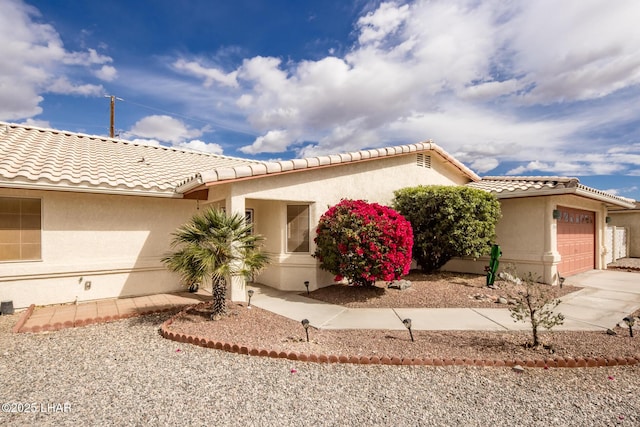 view of front of property with an attached garage, a tile roof, concrete driveway, and stucco siding