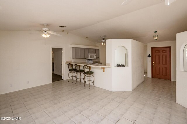 kitchen with ceiling fan, gray cabinetry, white appliances, a breakfast bar, and light countertops