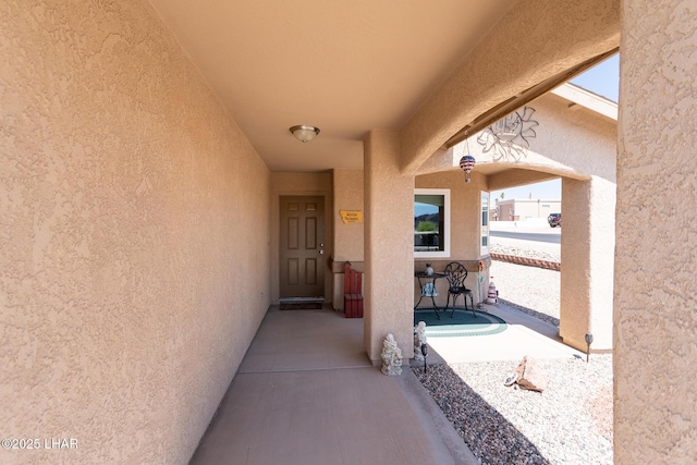 view of exterior entry featuring a porch and stucco siding