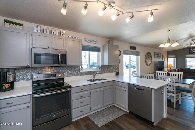 kitchen featuring stainless steel appliances, a sink, gray cabinetry, a peninsula, and a notable chandelier