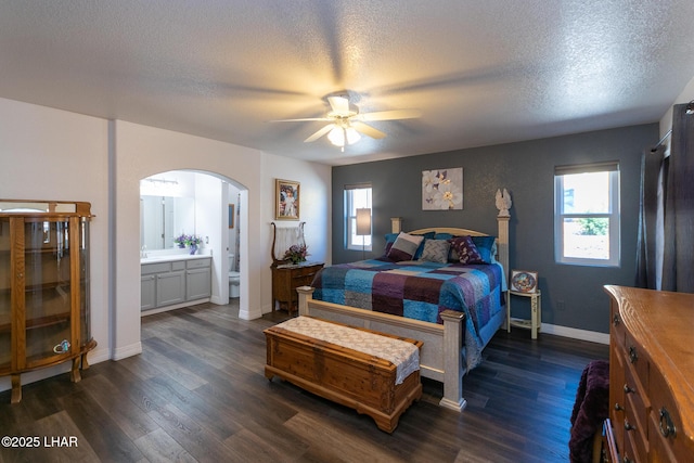 bedroom featuring a textured ceiling, arched walkways, dark wood-type flooring, and multiple windows