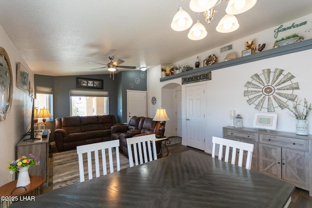 dining space with ceiling fan with notable chandelier, wood finished floors, visible vents, and arched walkways