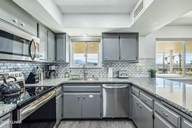 kitchen with visible vents, appliances with stainless steel finishes, a sink, and gray cabinetry