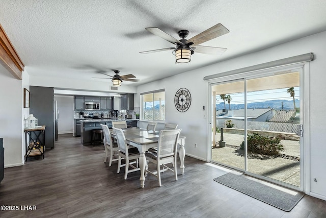 dining space featuring dark wood-type flooring, a textured ceiling, and baseboards