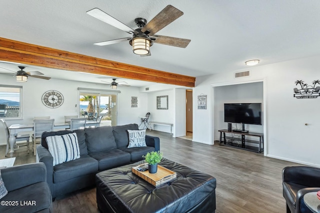 living area featuring a ceiling fan, visible vents, baseboards, beamed ceiling, and dark wood finished floors