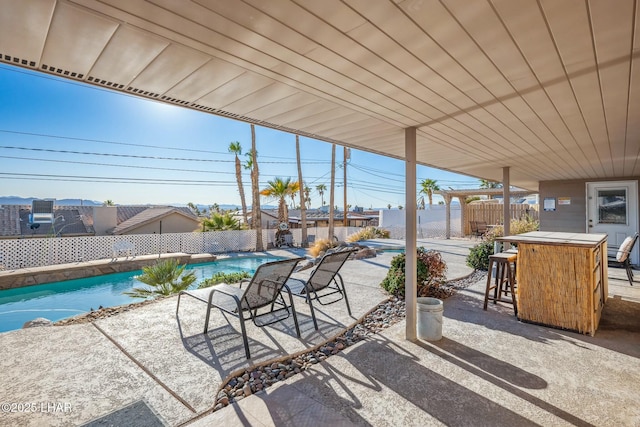 view of patio with fence, outdoor dry bar, and a fenced in pool