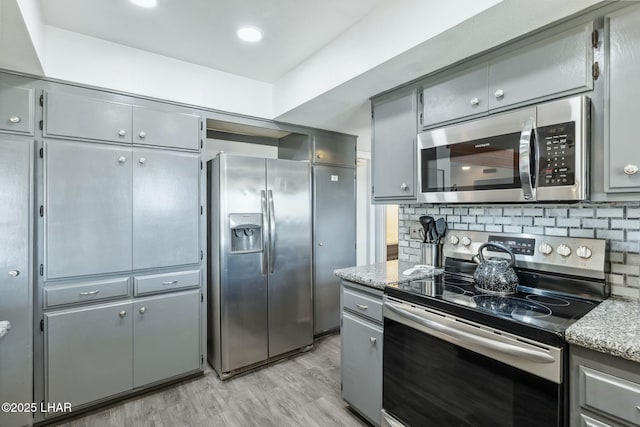 kitchen with stainless steel appliances, backsplash, and gray cabinetry