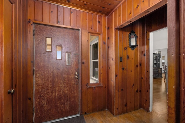 entrance foyer with wood walls and hardwood / wood-style floors