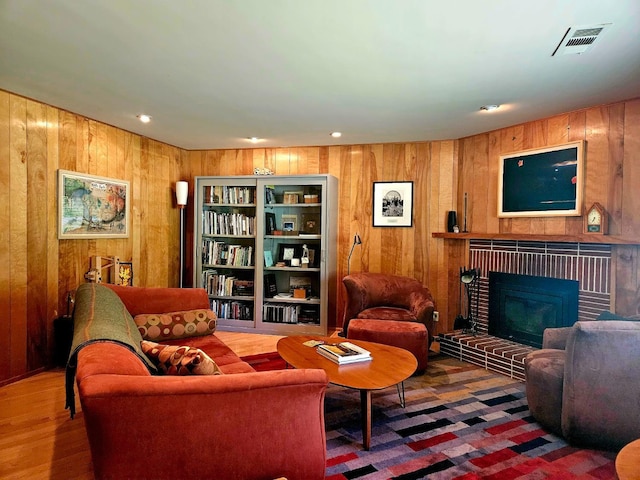 living room with a brick fireplace and wood walls