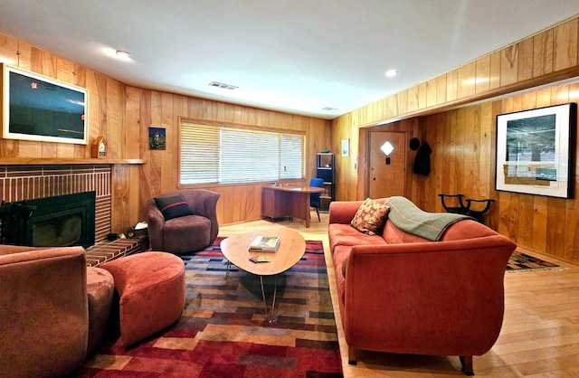 living room with a fireplace, hardwood / wood-style flooring, and wooden walls